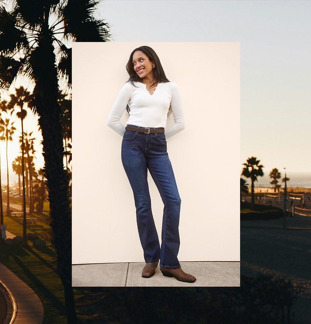 Woman standing against a wall wearing Lee Bootcut Jeans.
