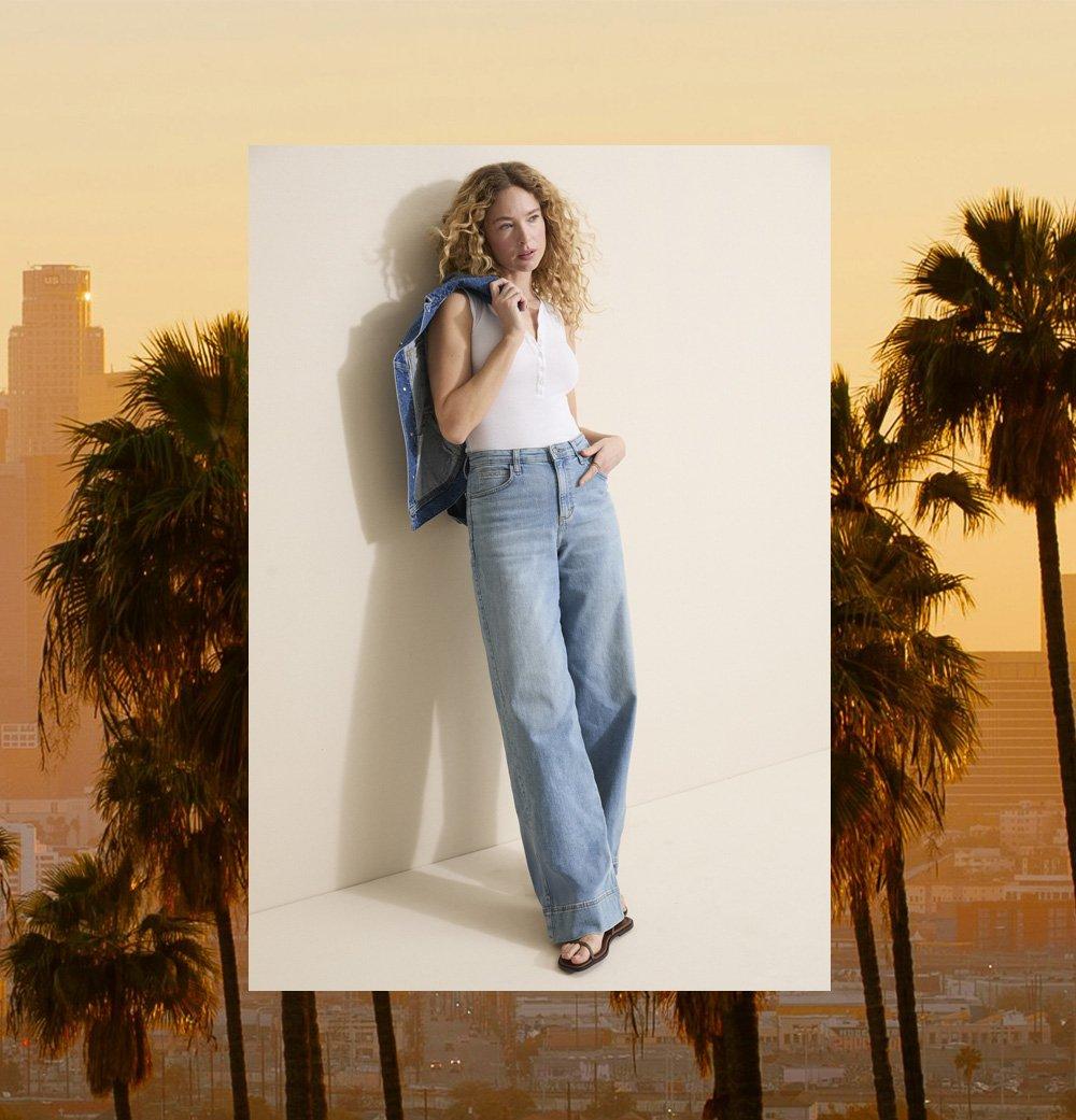 Woman standing against a wall wearing Lee Trousers.