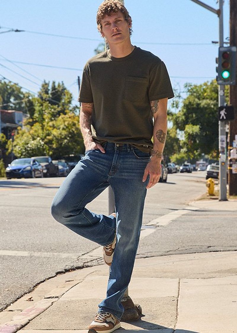 Man standing on a street corner wearing Lee stretch denim. 